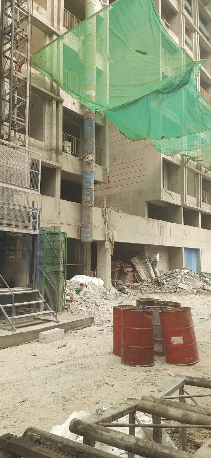 Construction debris chute discharge point above the rubble collection area at a Pune building site