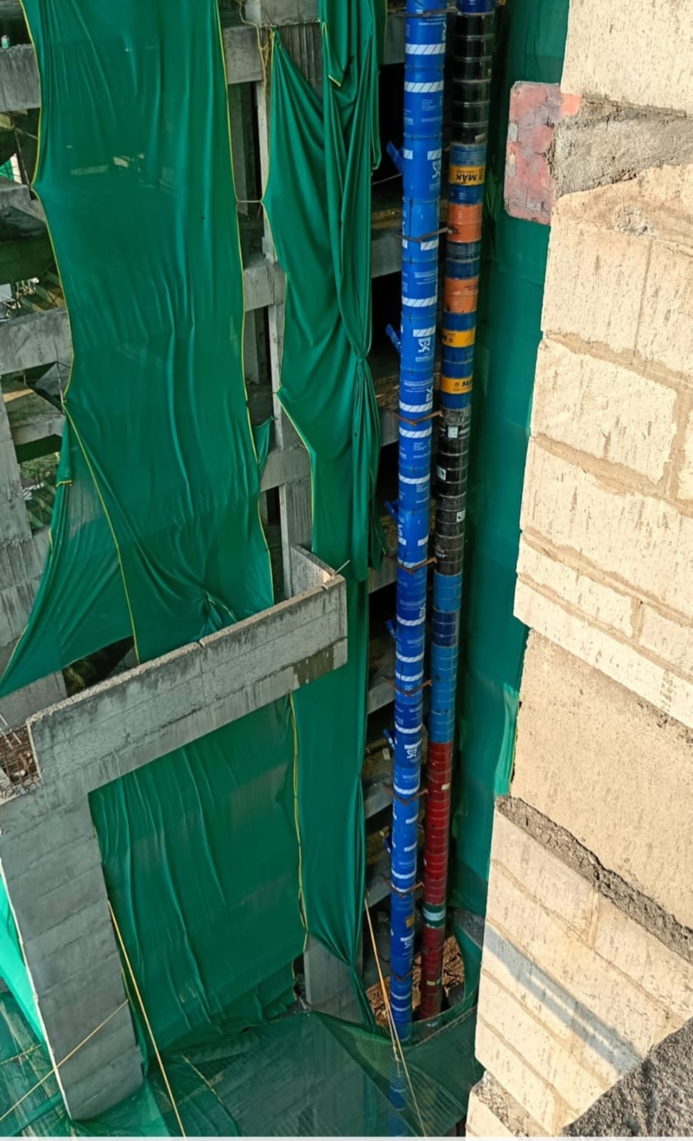 Twin debris chutes installed between high-rise building sections at a construction site in Pune